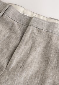 Világosbarna lenvászon nadrág finom, függőleges csíkokkal, sima derékrésszel és szabott kialakítással. Texturált anyag puha felülettel.
