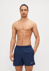 Tengerészkék úszóshort, könnyű anyagból készült, rugalmas derékkal és egy kisebb fehér Nike logóval a bal lábon.