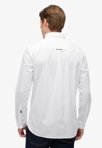 Witte lange mouwen shirt met een puntige kraag, knoopmanchetten en een centrale achternaad; gemaakt van gladde stof met een normale pasvorm.