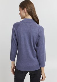 Violeta adīta džemperis ar trīs ceturtdaļu piedurknēm, ribotām malām un gludu tekstūru. Aizmugurējā skata dizains ir vienkāršs un bez rotājumiem.