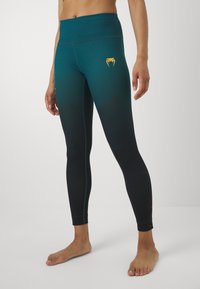 Leggings a vita alta in gradiente turchese e nero. Presentano un logo dorato, dettagli in rete e cuciture contornate per un effetto aggiuntivo.