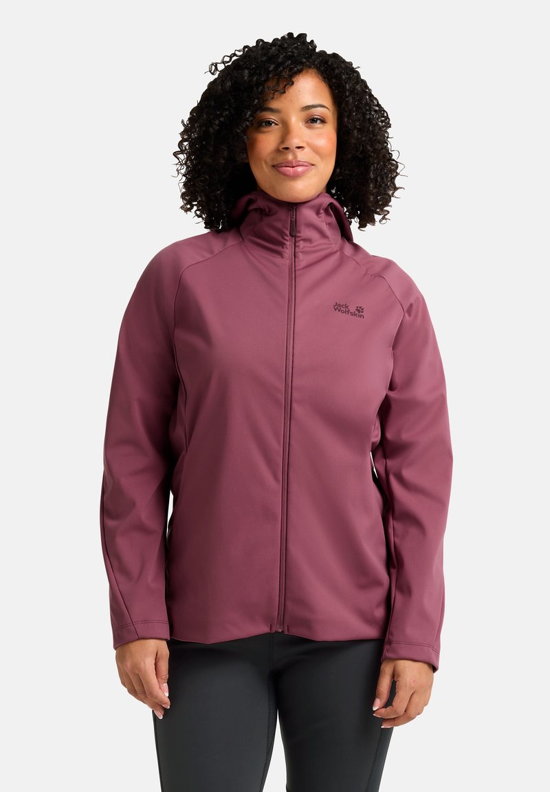 Giacca softshell viola con colletto alto e chiusura con zip. Presenta una texture liscia e un branding discreto. Indossata sopra pantaloni neri.