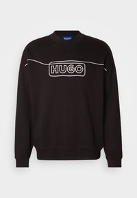 Fekete pamut pulóver, amely kerek nyakkivágással, hosszú ujjakkal és egy fehér "HUGO" logóval rendelkezik a mellkasán. Sima textúra.
