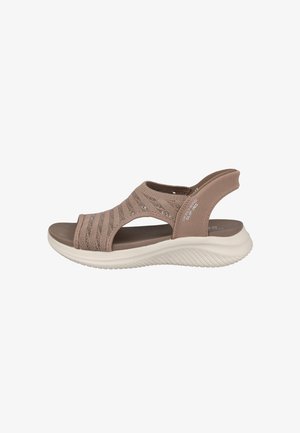 Sandalia taupe sin cordones con parte superior de punto, suela blanca acolchada y tira abierta en el talón, diseñada para comodidad y soporte casual.