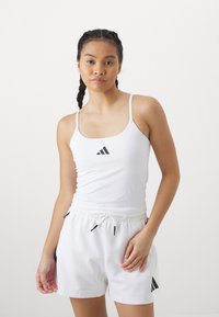 Witte sport tanktop met dunne bandjes en een zwart logo, gecombineerd met witte short met trekkoord en zijzakken, afgewerkt met zwarte accenten.