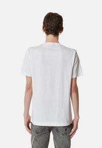 T-shirt bianca in cotone con collo tondo e maniche corte, caratterizzata da una linea dritta e una texture liscia, vista da dietro.