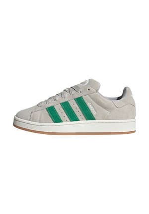Light gray suede sneaker with three green stripes, rubber sole, and white accents. Features a round toe and flat lace-up design.