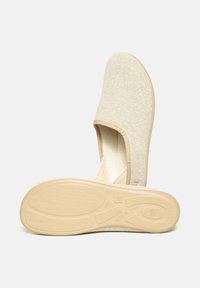 Light beige slip-on shoe made of fabric with textured rubber sole marked "Made in Spain," shown from side and bottom views.