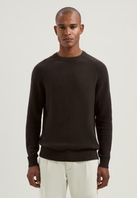 Mörkbrun crew neck-tröja med en texturerad yta, ribbade muddar och nederkant, med en avslappnad passform och långa ärmar.