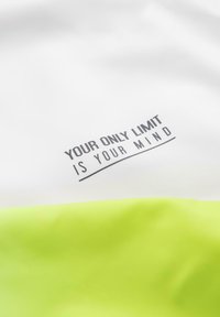 Phrase motivante "Votre seule limite est votre esprit" en texte noir sur tissu blanc au-dessus d'une section de tissu jaune-vert vif.