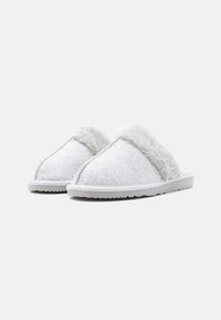 Grijze gevoerde slippers met een zachte, fluffy grijze bontafwerking. Kenmerken zijn een platte witte zool, driehoekig ontwerp en zichtbare stiksels.