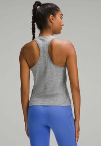 Gray athletic tank top with a racerback design, featuring textured fabric. Worn with blue leggings, displaying a fitted silhouette.