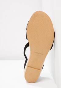 Semelle de sandale avec fond beige texturé, brides noires, taille 37, marquée "Made in Spain", photographiée debout sur une surface blanche.