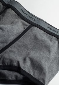 Grå bomullsboxershorts med ett svart elastiskt midjeband som har "intimissimi" i ett upprepande mönster. Slät textur och slimmande design.