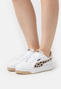 Vita sneakers i läder med en beige leopardmönstrad accent på sidan, texturerad gummisula och snören med varumärke på tungan.