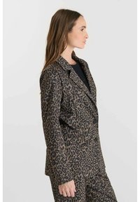 Blazer imprimé léopard avec un design à double boutonnage, revers cranté et deux poches avant. Le tissu allie une texture lisse à une coupe structurée.