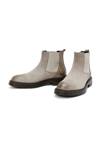 Botas de tobillo de ante gris con paneles laterales elásticos y lengüetas de tirón. Punta redonda, suela de goma gruesa y textura sutil. Diseño minimalista.