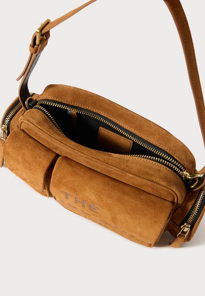 Τσαντάκι χιαστί από καφέ σουέντ με διπλά φερμουάρ. Διαθέτει μεταλλικά στοιχεία σε χρυσό τόνο και ανάγλυφο λογότυπο στο μπροστινό μέρος. Ρυθμιζόμενο λουρί από δέρμα.