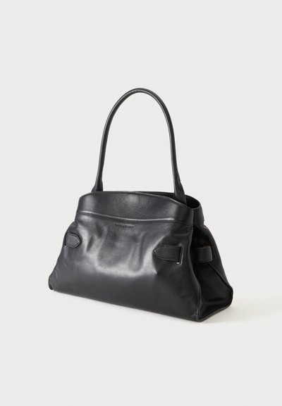 Sac à main en cuir noir avec poignées arrondies, forme rectangulaire et détails de surpiqûres subtils, posé sur un fond blanc.