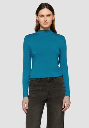 Teal lange mouw top met een hoge halslijn, gemaakt van een gladde stof. Gepaard met donkergrijze broeken met een klassiek vijf-pocket ontwerp.