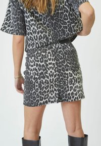 Fustă din denim cu print leopard, cu o croială ajustată, două buzunare pe spate și un talie medie. Schema de culori negru și gri, cu cusături vizibile.