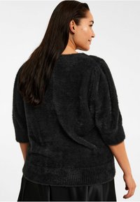 Sort fuzzy sweater med korte pufærmer, rund halsudskæring og tekstureret stof. Viser ribbet kant og blød, fyldig fremtoning.