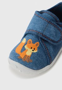 Denim sko med en velcrorem, grå gummisula och en broderad rävdesign i orange och brunt på tåspetsen.