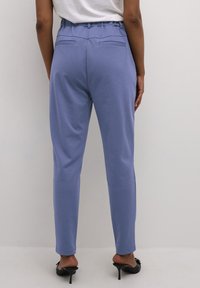 Lichtblauwe broek met een elastische tailleband, taps toelopende benen en twee achterzakken, gemaakt van een soepel, zacht materiaal.