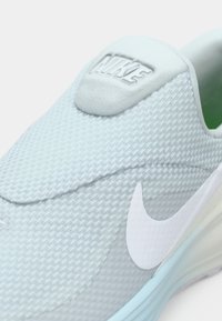 Ανοιχτά γαλάζιο αθλητικό παπούτσι Nike με υφασμάτινο επάνω μέρος, λείο γκρι γλώσσα, λευκό λογότυπο Swoosh και απαλό πράσινο εσωτερικό.