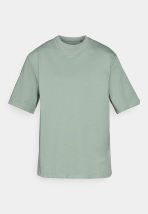 Gaiši zaļa īsās piedurknes t-kreklā, izgatavota no mīksta auduma, piedāvā komplektu ar apaļu kakla izmēru un smalku logo, kas izdrukāts priekšā. Pamata, kastveida forma.