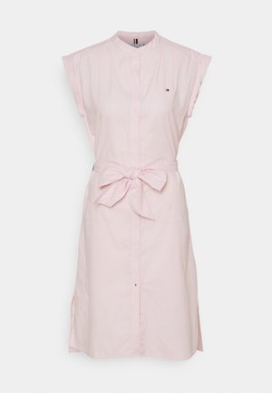 Robe chemise sans manches rose clair avec des boutons sur le devant et une ceinture nouée à la taille, avec un petit logo sur la poitrine.