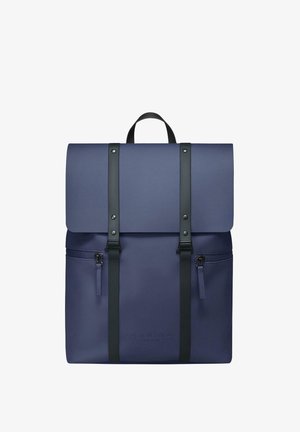 Tamsiai mėlynas kuprinė su sulankstomu dangteliu, juodomis diržais, priekinė zip kišenė ir iškilmingu logotipu. Pagaminta iš tvirto, lygaus paviršiaus medžiagos.