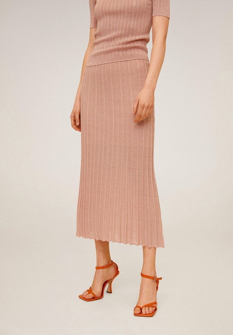 Conjunto de dos piezas tejido en rosa claro que incluye una blusa de manga corta con canalé y una falda midi con dobladillo acampanado, combinado con sandalias de tacón alto naranjas.