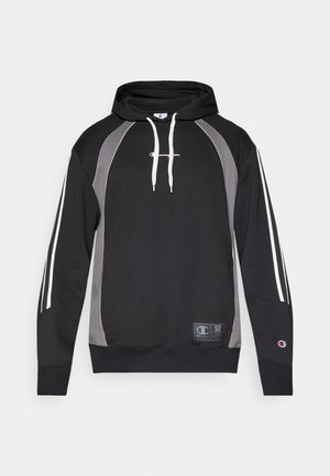 Sort hættejakke med grå sidepaneler, hvide accentstriber, snoretræk i hætten, ribbede manchetter og et logopatch forneden.