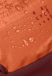 Tissu orange résistant à l'eau avec une surface texturée, présentant des gouttes d'eau. Accent violet foncé en bas. Matériau recyclé indiqué.