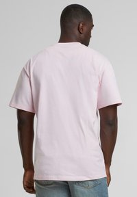 Light pink cotton t-shirt with short sleeves, a round neckline, and a relaxed fit. Smooth texture and minimal detailing.
