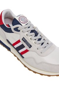 Scarpa sportiva beige con tomaia in suede e tessuto, caratterizzata da strisce rosse e blu navy, punta rotonda e suola in gomma testurizzata.