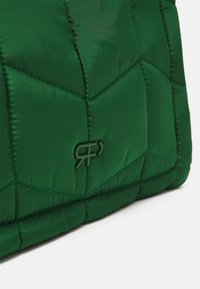 Tissu vert matelassé avec des coutures géométriques et un logo "RP" entrelacé en relief embossé sur la surface.