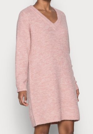 Light pink knitted sweater dress with a v-neck, long sleeves, and ribbed texture. Side slits at hem for ease of movement.