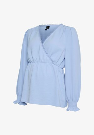 Blouse portefeuille bleu clair à manches longues, avec un décolleté en V, des poignets élastiqués et une bordure décorative festonnée le long du décolleté.
