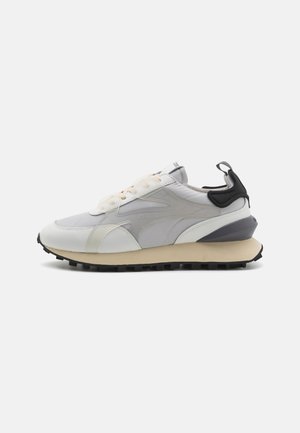 Sneaker mit einem Obermaterial aus gemischten Materialien in Hellgrau, mit weißen und schwarzen Akzenten. Verfügt über eine klobige Sohle mit strukturiertem Profil und Schnürsystem.