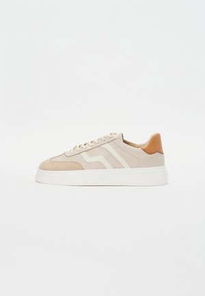 Sneakers beige con una combinazione di pelle liscia e camoscio. Presentano accenti bianchi, lacci piatti e una leggera suola piatta.