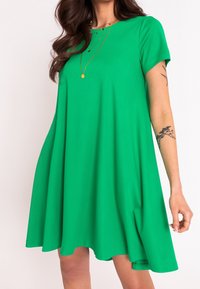 Grünes kurzärmliges Kleid aus glattem Stoff, mit einer A-Linien-Silhouette, die knapp über dem Knie endet, und einem runden Ausschnitt.