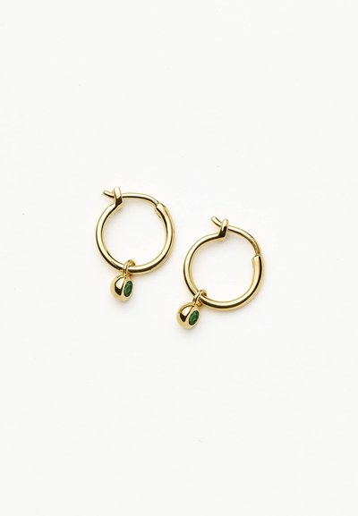 Orecchini a cerchio in oro con un design rotondo e liscio, con un piccolo gemma verde che pende da ciascun cerchio.