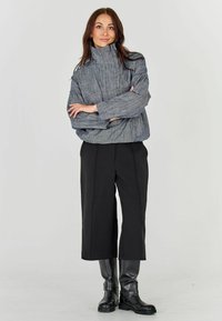 Halli tekstuuriga kõrge kaelusega pluus, millel on vabalt langev lõige, koos mustade laiade pükstega ja mustade põlvekõrguste saapadega.