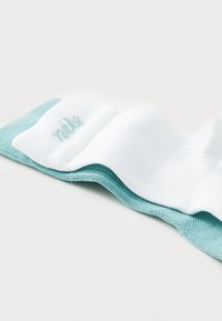 Bijela čarapa s tirkiznim naglaskom na manžetu, s rebrastom teksturom i suptilnim Nike logotipom. Izrađena od mekanog, rastezljivog materijala.
