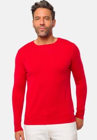 Pull-over rouge à manches longues en mailles lisses, avec un col rond et des poignets et un ourlet côtelés. Design simple et uni.