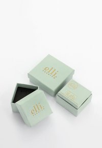 Mintgröna presentlådor med guldtext, i olika storlekar; en har en svart insida. Slät yta, enkel design och inga ytterligare detaljer.