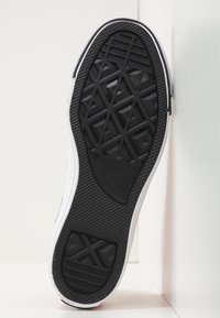 Suola in gomma nera di una sneaker con un motivo testurizzato per una migliore aderenza, dettagli laterali bianchi e un logo impresso al centro.