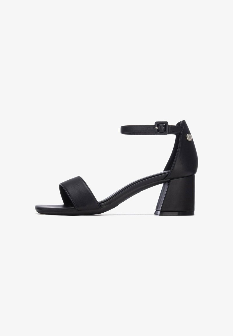 Sandalias negras de cuero con tacón, que cuentan con una tira ancha en la parte delantera, una correa ajustable alrededor del tobillo y un tacón grueso para mayor estabilidad.